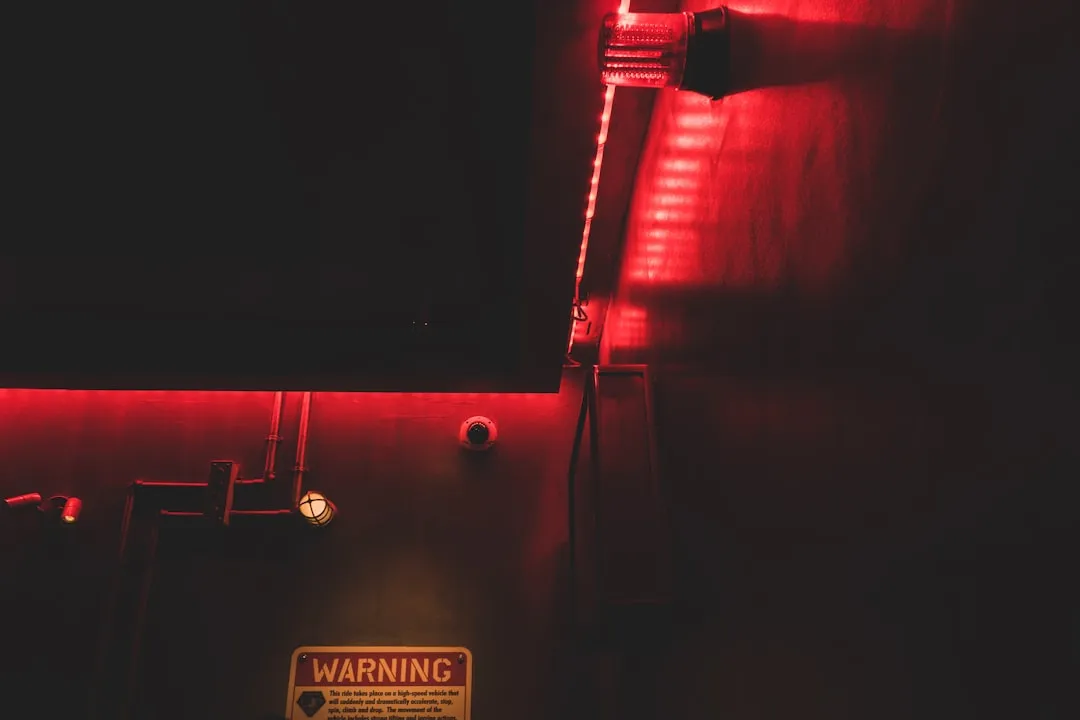 a dark room with a red light and a warning sign