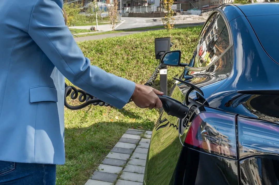 Person charging an electric car at charging station.