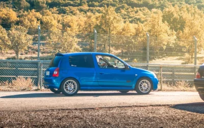 blue 5 door hatchback parked beside gray metal fence during daytime