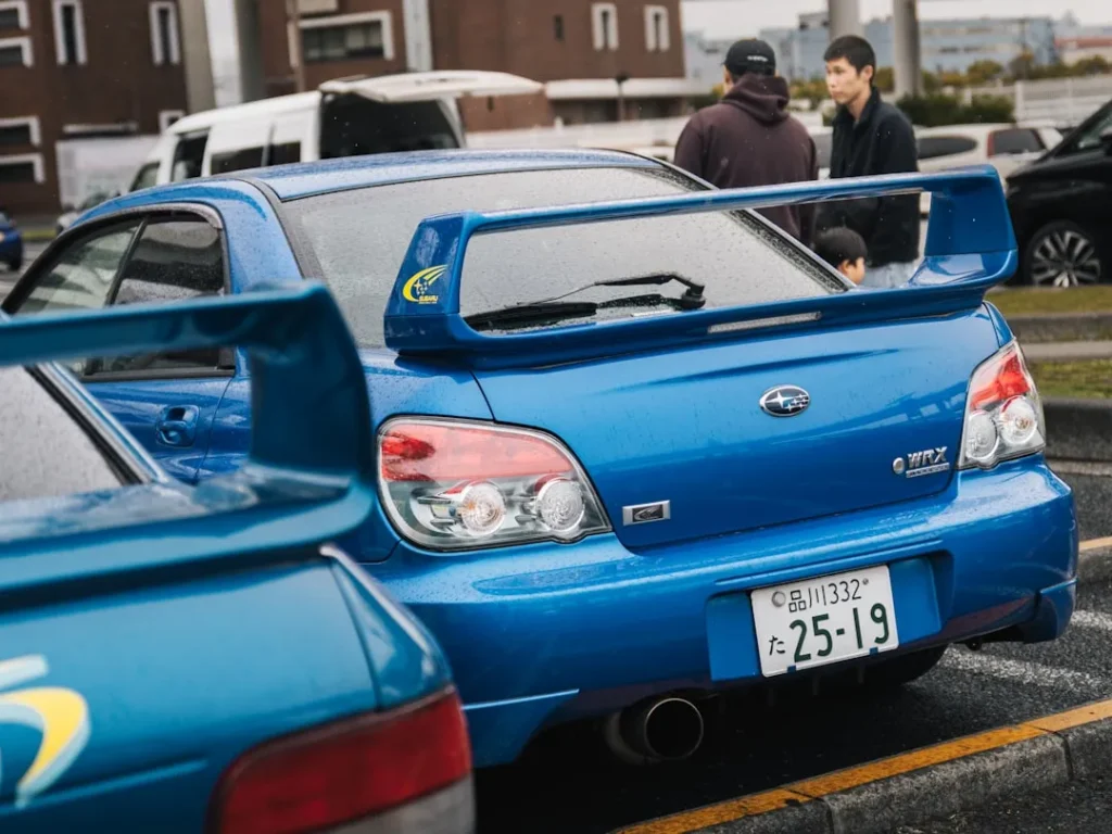 Two blue subaru wrx cars parked side by side