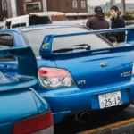 Two blue subaru wrx cars parked side by side