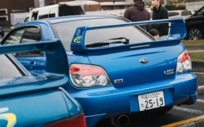 Two blue subaru wrx cars parked side by side