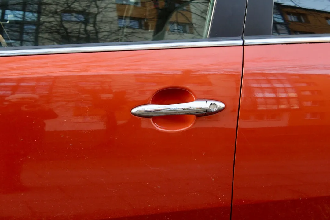 An orange car door with a silver handle.