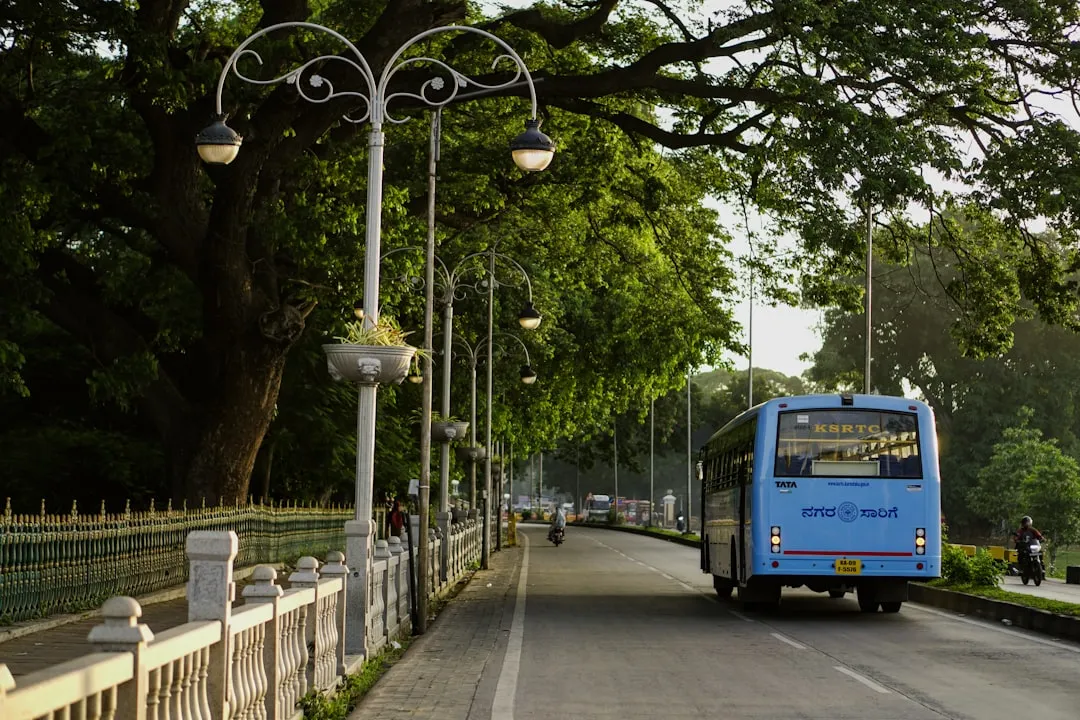A blue bus driving down a street next to a fence