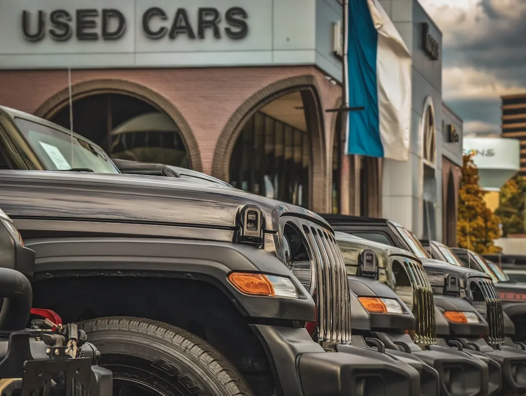 a row of parked cars in front of a used car store