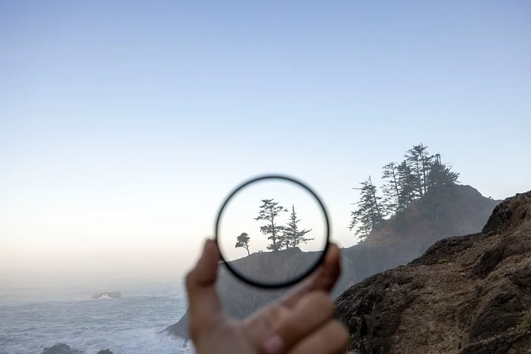 a person holding a magnifying glass looking at the ocean