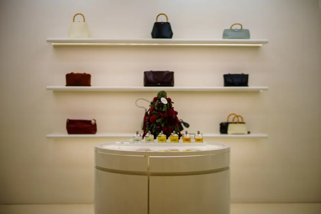 Designer handbags displayed on illuminated shelves above a display table.